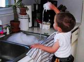 Child playing with water at kitchen sink